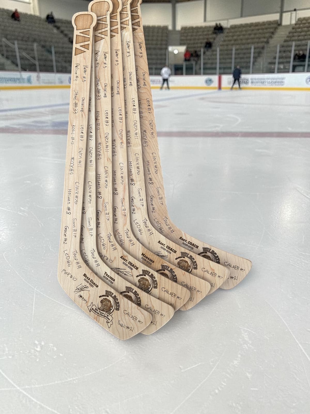 Engraved wooden hockey stick trophies for a youth team, laid out with player names and numbers