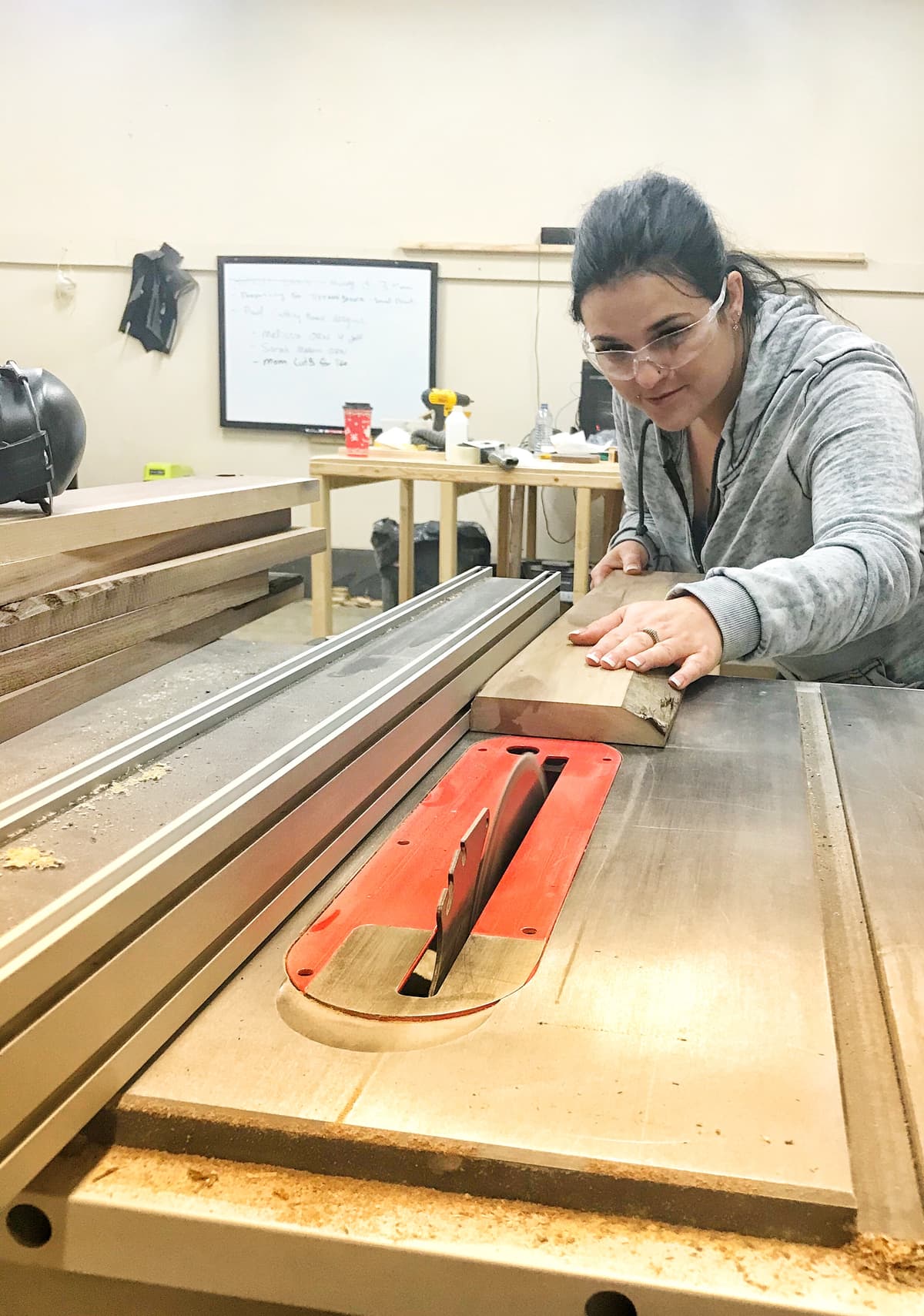 Krystle guiding a board through the table saw