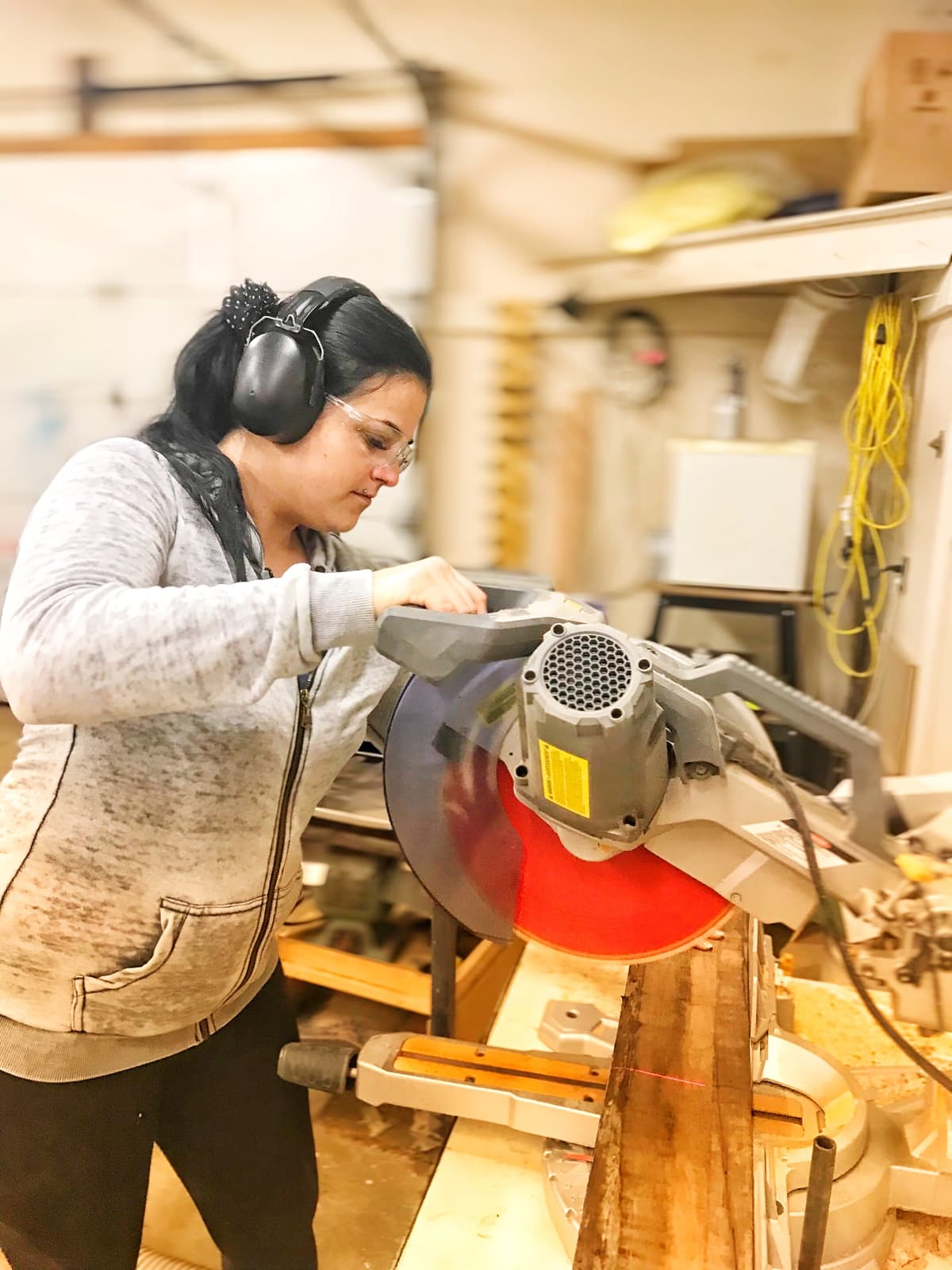 Krystle using a saw to help in the workshop