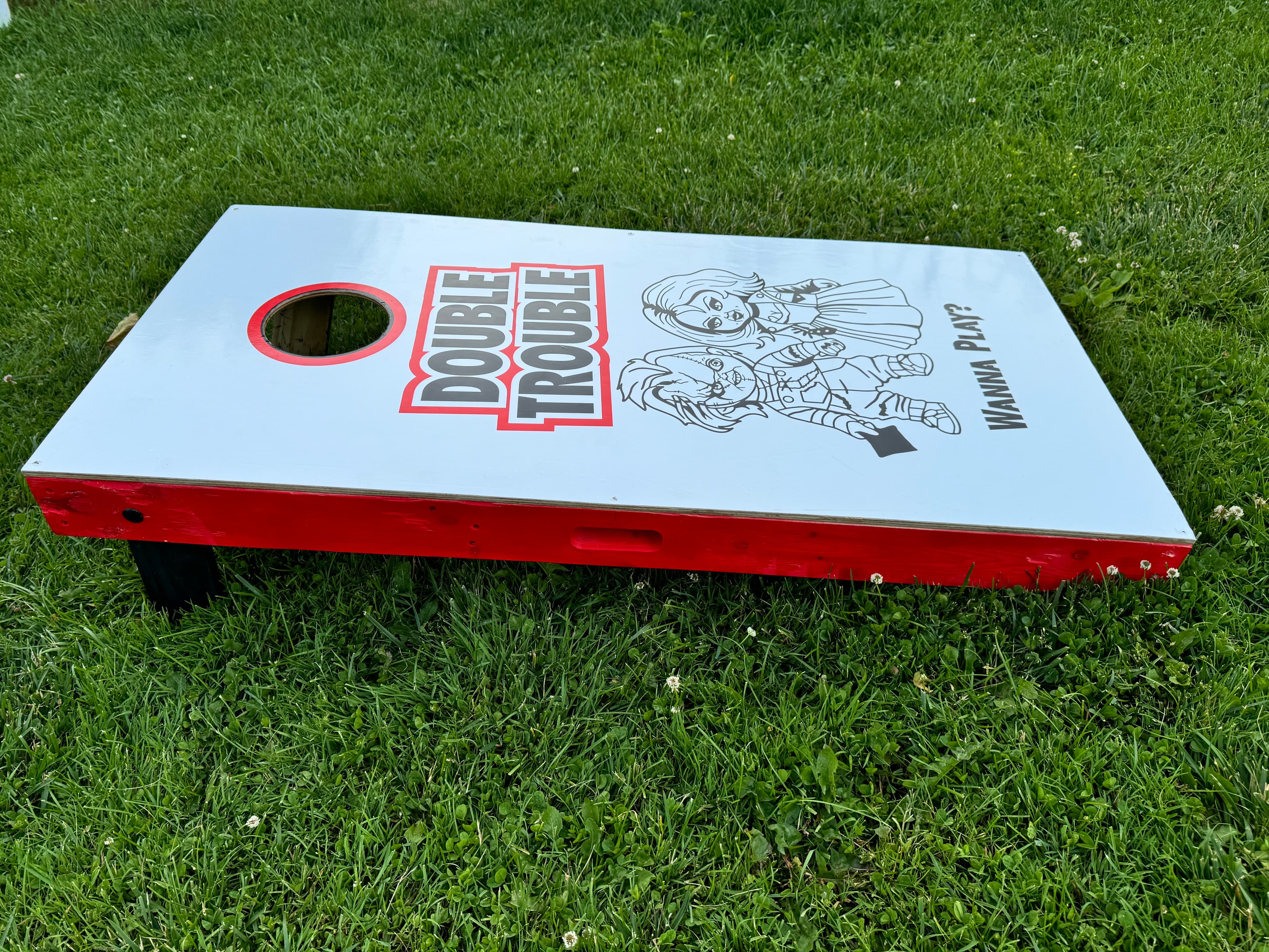 Side angle of the Bride of Chucky cornhole board showing the red painted sides and overall build quality on grass