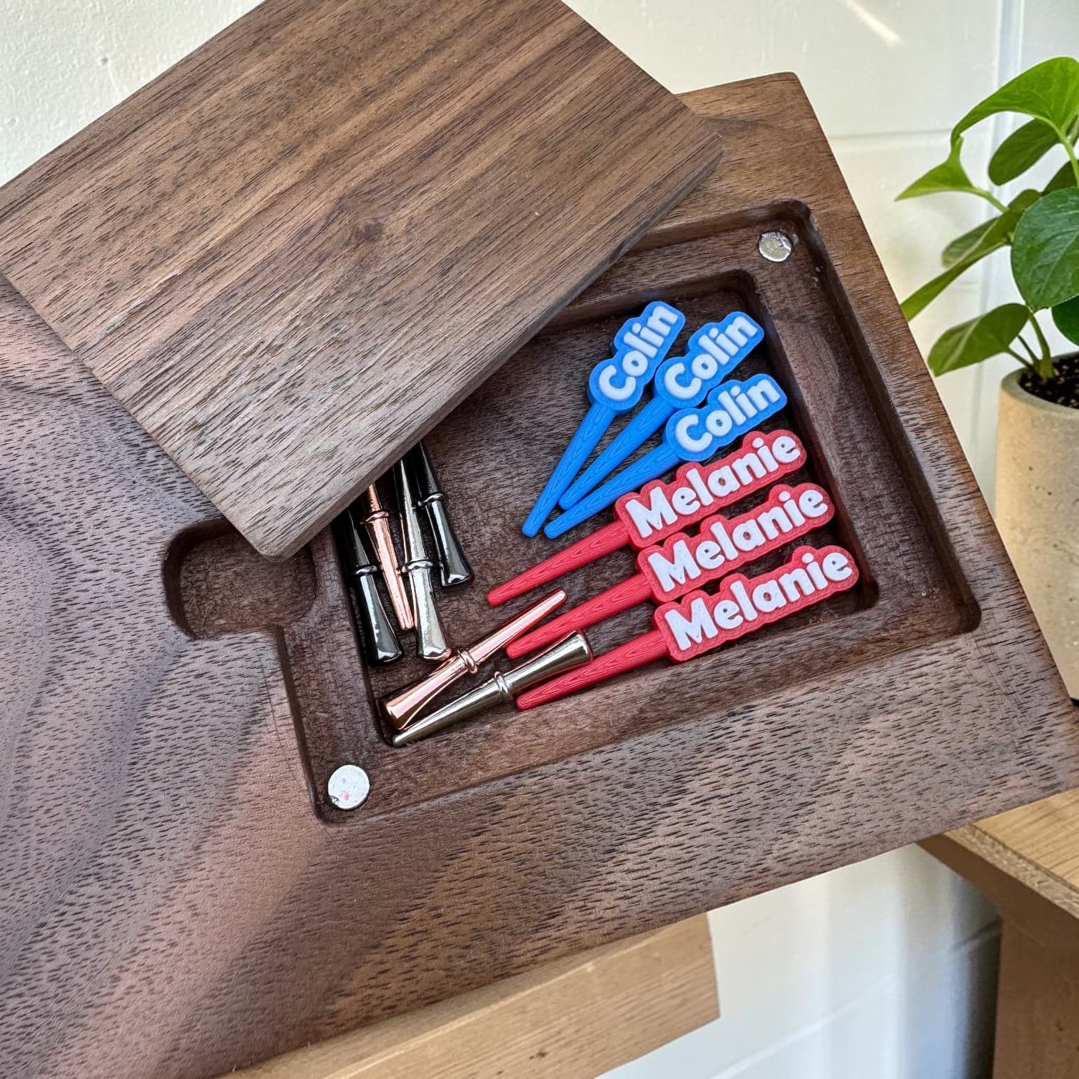 Personalized pegs engraved with names, in custom colors, stored in the board's back pocket