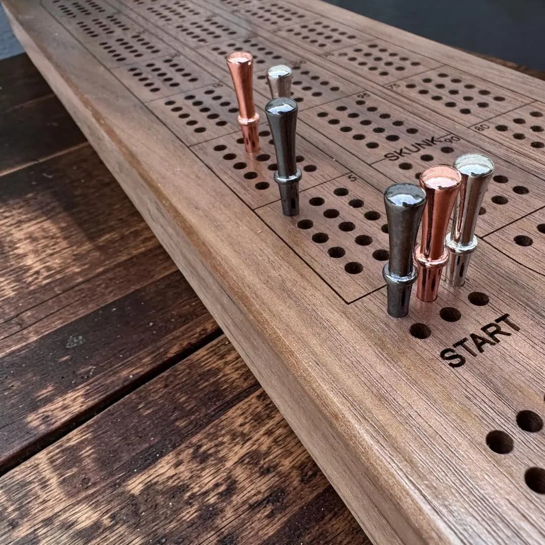 Personalized cribbage board shown at an angle with metal pegs in the track, showing the thickness of the solid hardwood