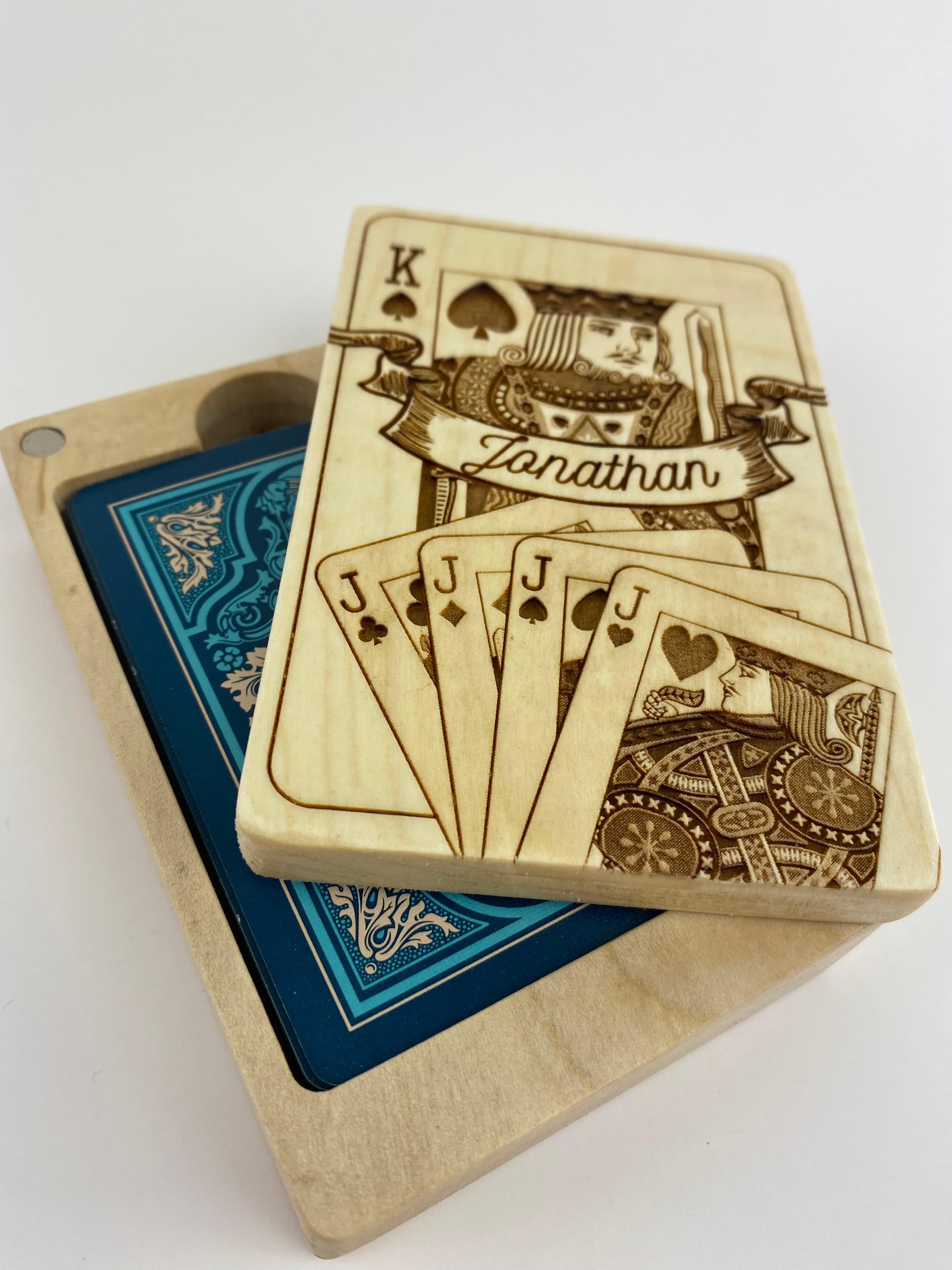 Close-up of a playing card box lid showing detailed laser-engraved King card artwork with Jonathan's name in a banner