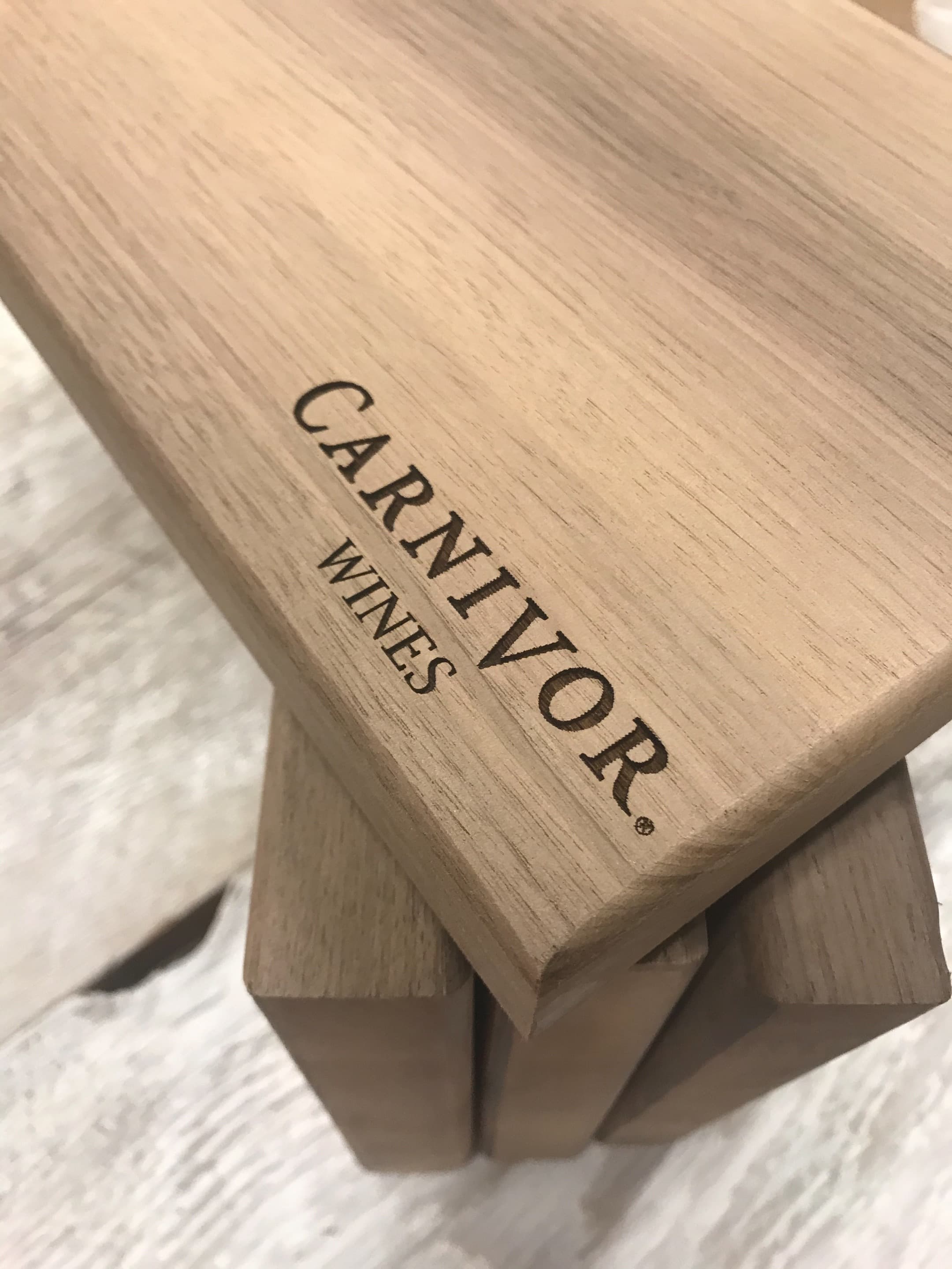Close-up of stacked walnut steak boards with Carnivor Wines branding