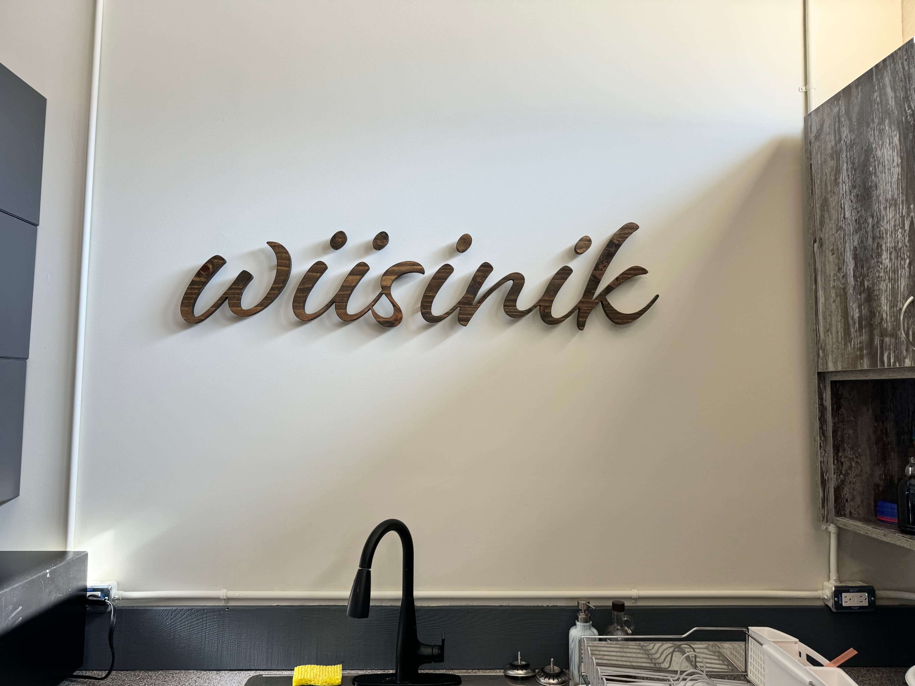 Standoff signage reading wiisinik mounted above the kitchen sink at GBNWA
