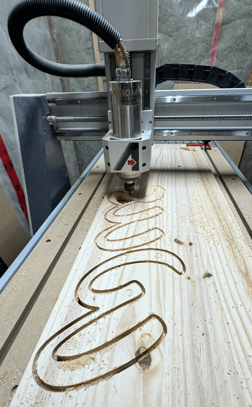 CNC machine cutting script letterforms from wood for the GBNWA signage