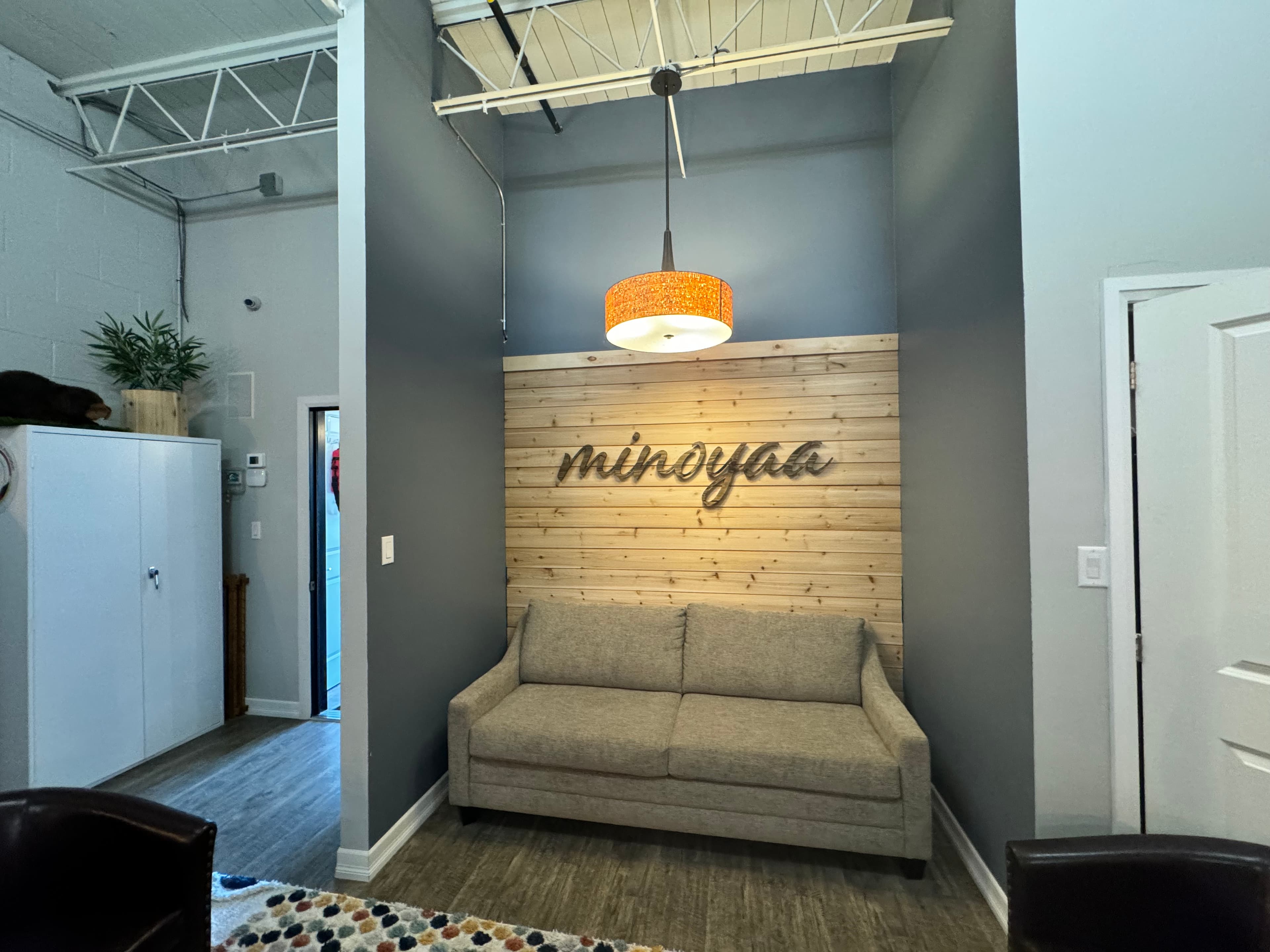 Wide shot of the minoyaa sign mounted on a cedar plank wall above a couch in the sitting area