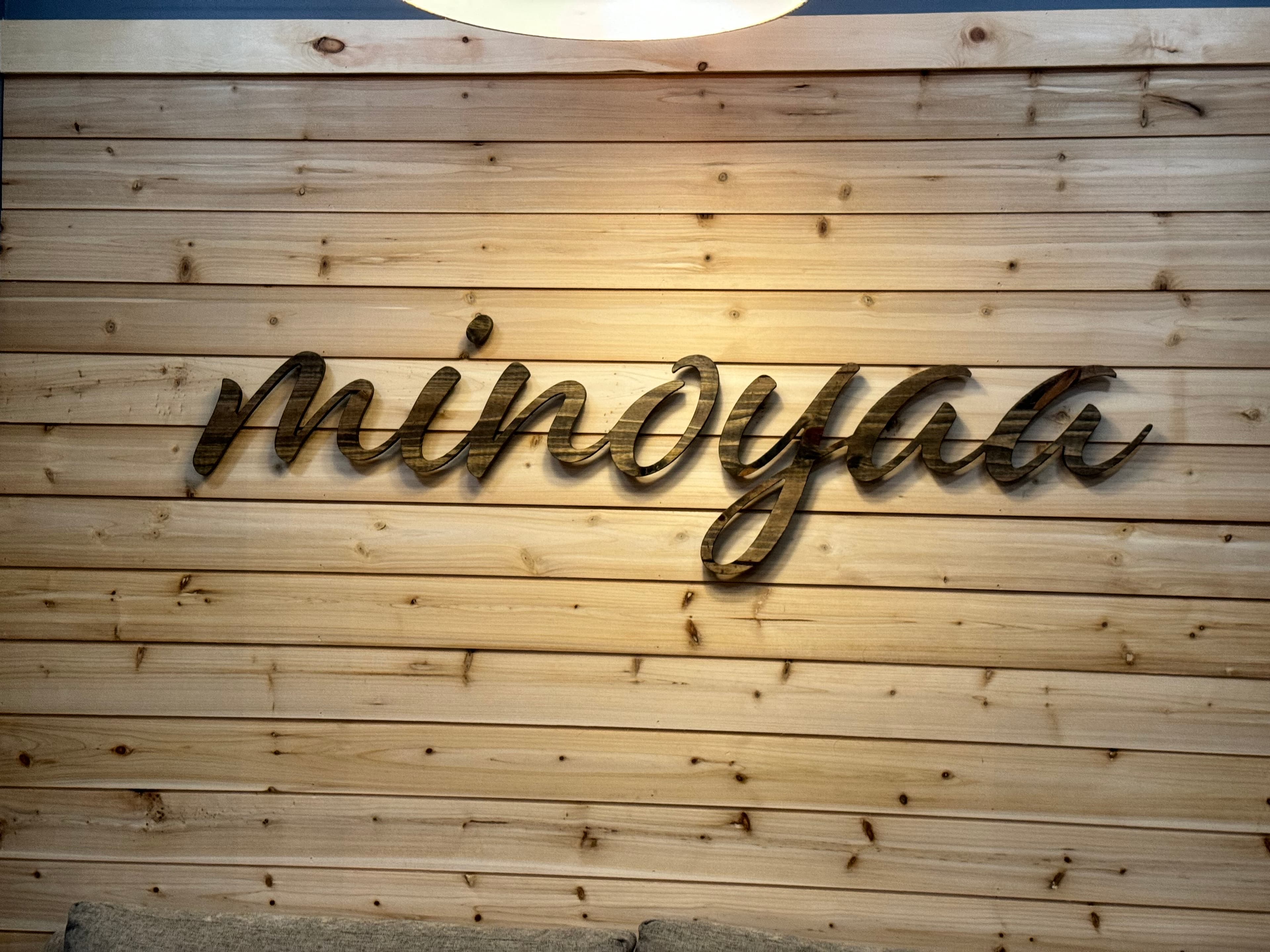 Close-up of the minoyaa standoff sign with warm pendant lighting casting shadows