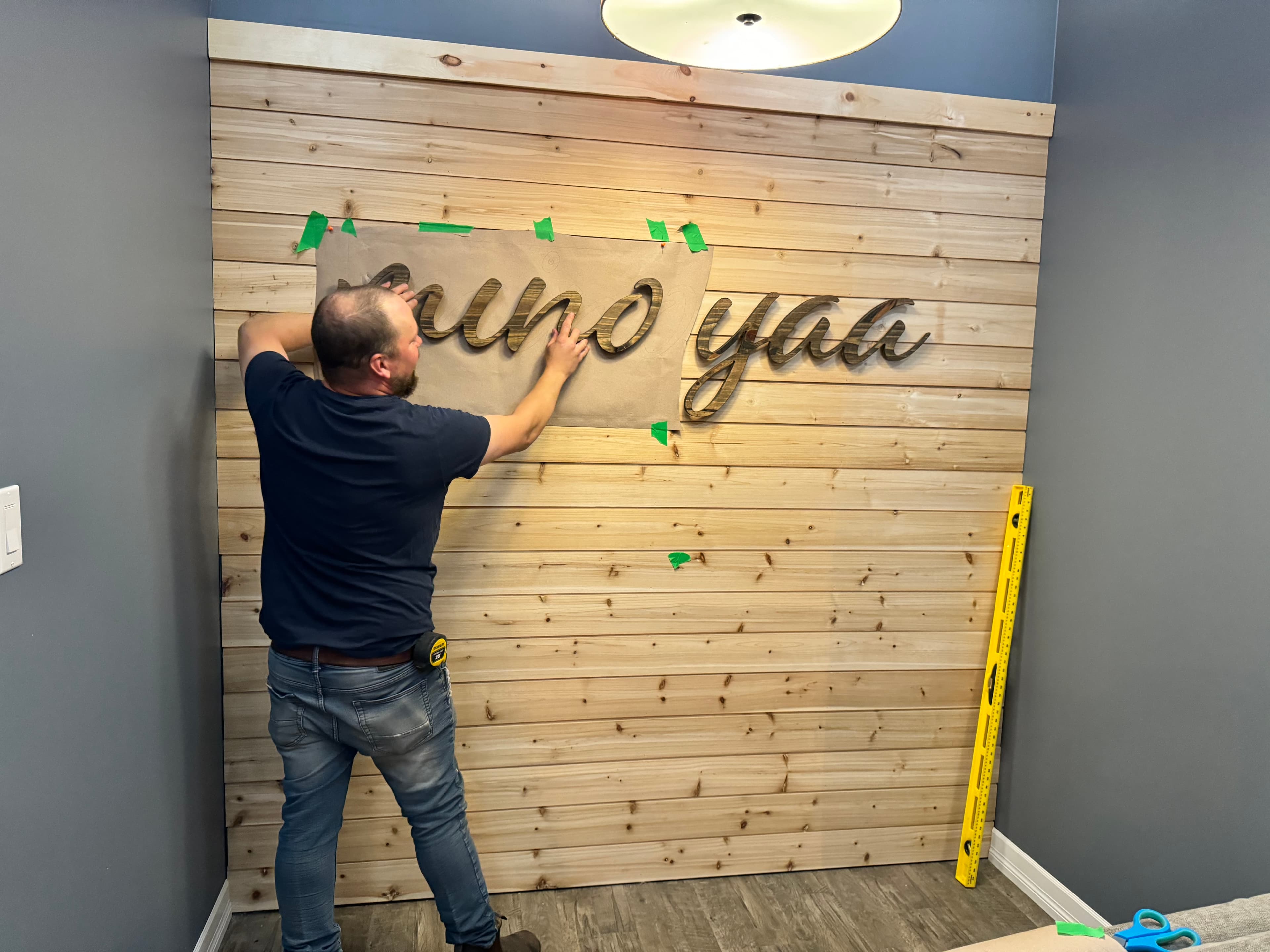 Mounting the wooden script letters onto the standoff pegs on the wall